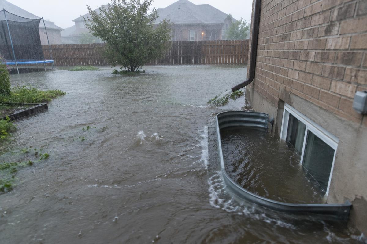 Floodwater surrounding a basement window well behind a Kitchener-area home during a storm